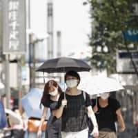 People walk in Tokyo\'s Ginza district with parasols amid the scorching summer heat Wednesday. | KYODO