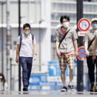 People walk in the Shinjuku area of Tokyo on Wednesday amid scorching summer heat. | KYODO
