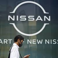 A man walks past Nissan\'s new logo at one of the automaker\'s showrooms in Tokyo last month. | AP