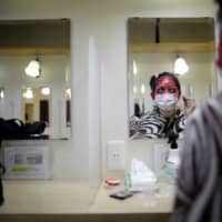 An actor dressed as a zombie puts makeup on before a coffin horror show performed by Kowagarasetai (Scare Squad)  in Tokyo on Aug. 5. | REUTERS