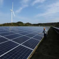 An engineer inspects solar panels at Banpu Power\'s solar plant in Awaji, Hyogo Prefecture. | BLOOMBERG