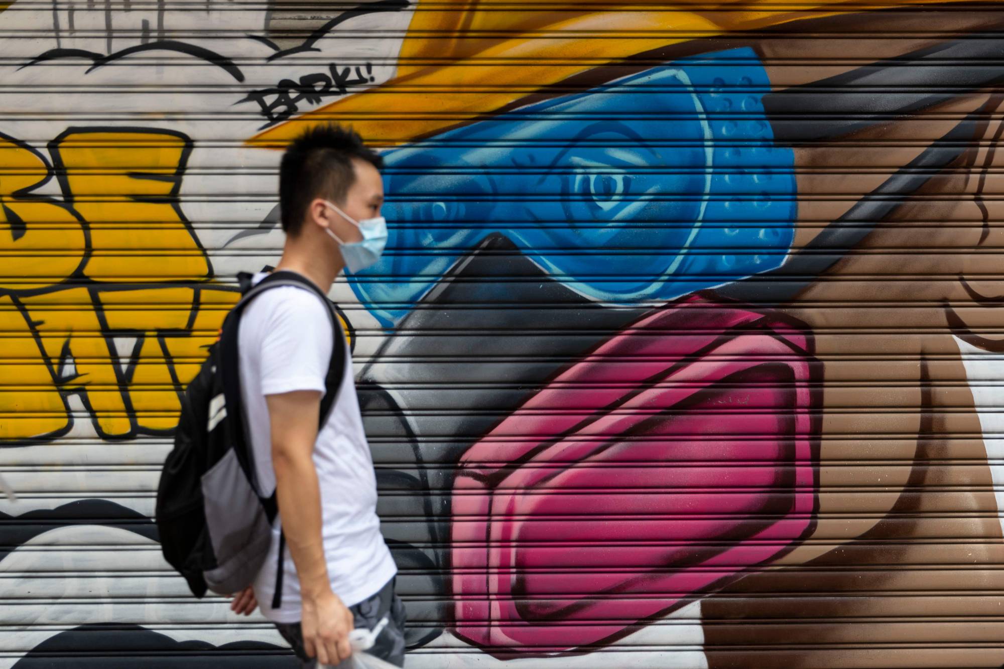 A man walks past a mural in Hong Kong on Sunday.  | AFP-JIJI