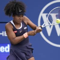Naomi Osaka hits a return against Dayana Yastremska, of Ukraine, during the third round of the Western and Southern Open in New York on Tuesday. | AP