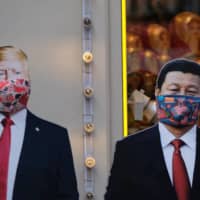 Cardboard cutouts of images of U.S. President Donald Trump and Chinese leader Xi Jinping adorned with protective masks are displayed in Moscow in March. | REUTERS