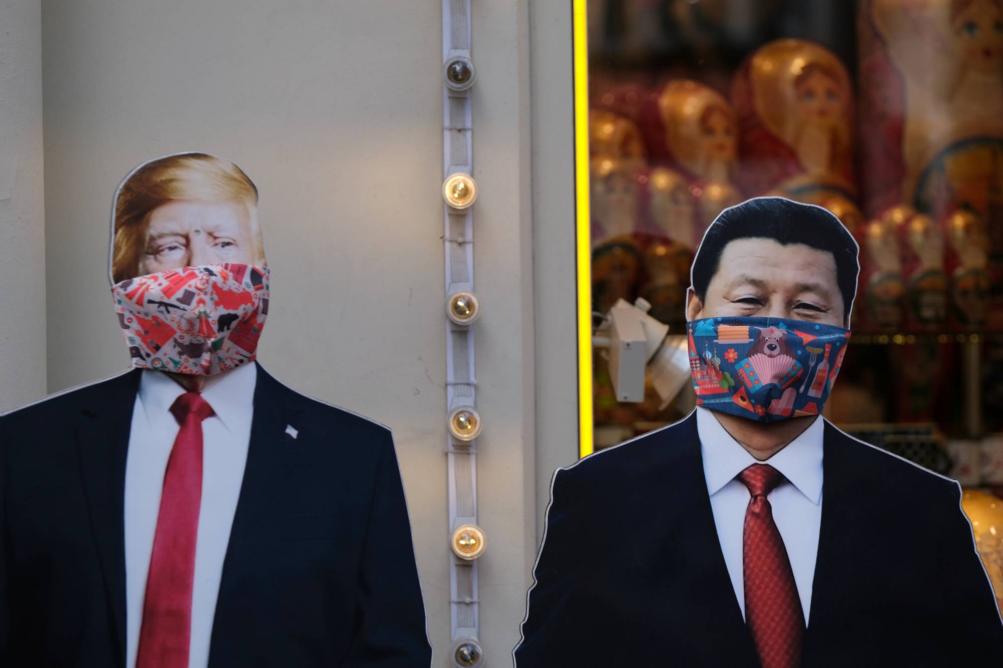 Cardboard cutouts of images of U.S. President Donald Trump and Chinese leader Xi Jinping adorned with protective masks are displayed in Moscow in March. | REUTERS