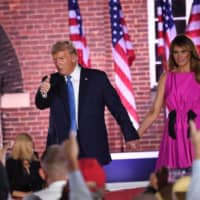 U.S. President Donald Trump holds hands with first lady Melania Trump at the conclusion of the third night of the Republican National Convention on Wednesday. | AFP-JIJI