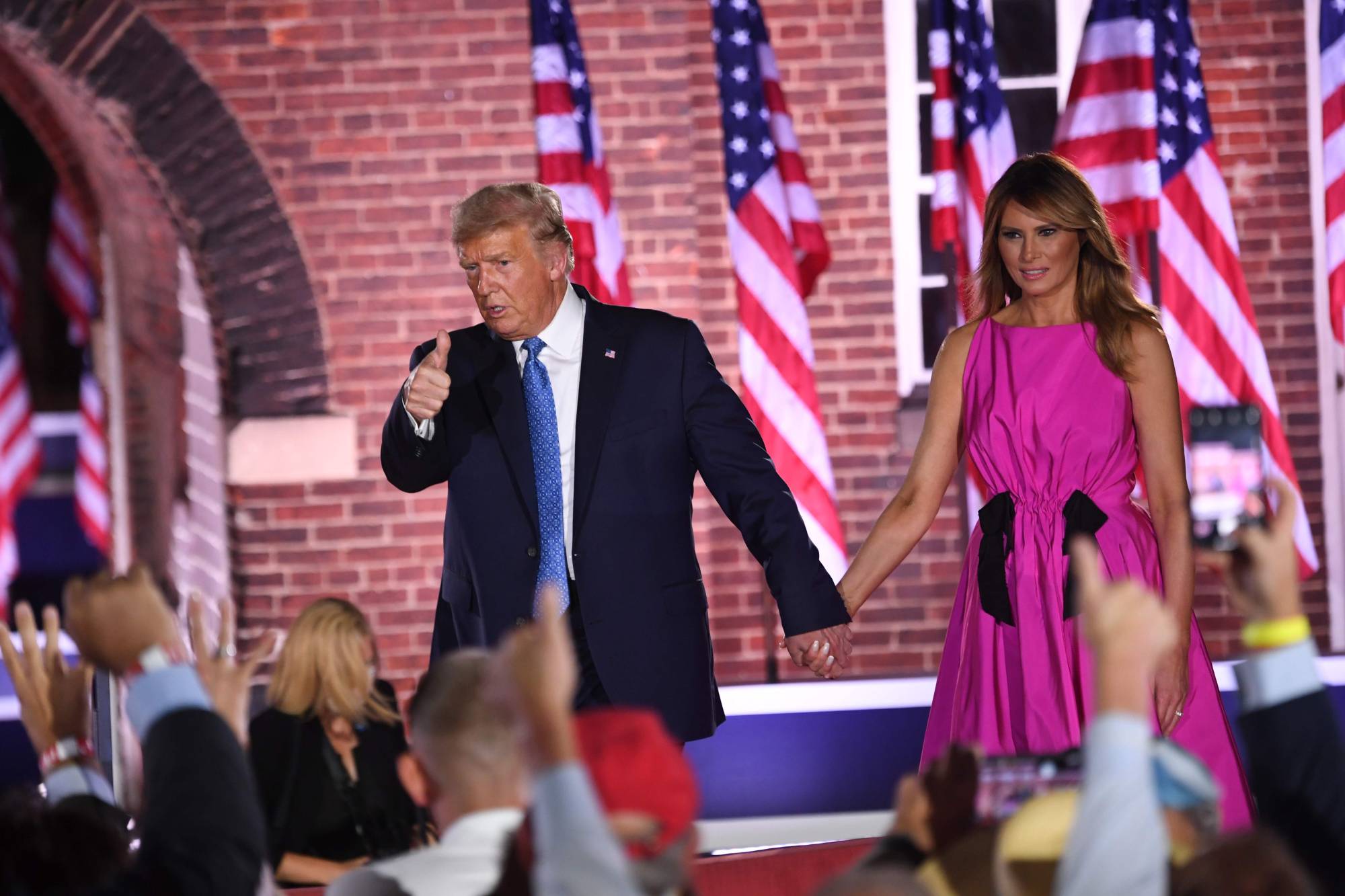 U.S. President Donald Trump holds hands with first lady Melania Trump at the conclusion of the third night of the Republican National Convention on Wednesday. | AFP-JIJI