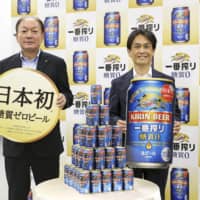 Kirin Brewery President Takayuki Fuse (left) holds a sign reading \"Japan\'s first\" in promoting its new zero-carb beer in Tokyo on Thursday. | KYODO