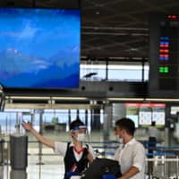An airline employee talks with a passenger at Narita International Airport in Chiba Prefecture on Aug. 19. | AFP-JIJI