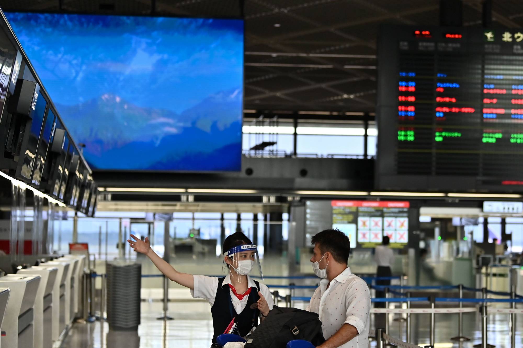 An airline employee talks with a passenger at Narita International Airport in Chiba Prefecture on Aug. 19. | AFP-JIJI