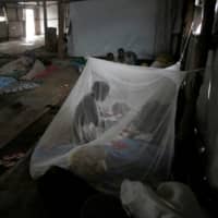 A South Sudanese refugee takes care of her baby under a mosquito net in a transit tent at a refugee camp in Uganda in 2017. Malaria affects more than 200 million people worldwide and killed an estimated 405,000 people in 2018 — most of them babies and children under five years old. | REUTERS