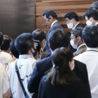 Deputy Prime Minister and Finance Minister Taro Aso (center, top) is surrounded by journalists at the Prime Minister\'s Office in Tokyo on Friday. | AP