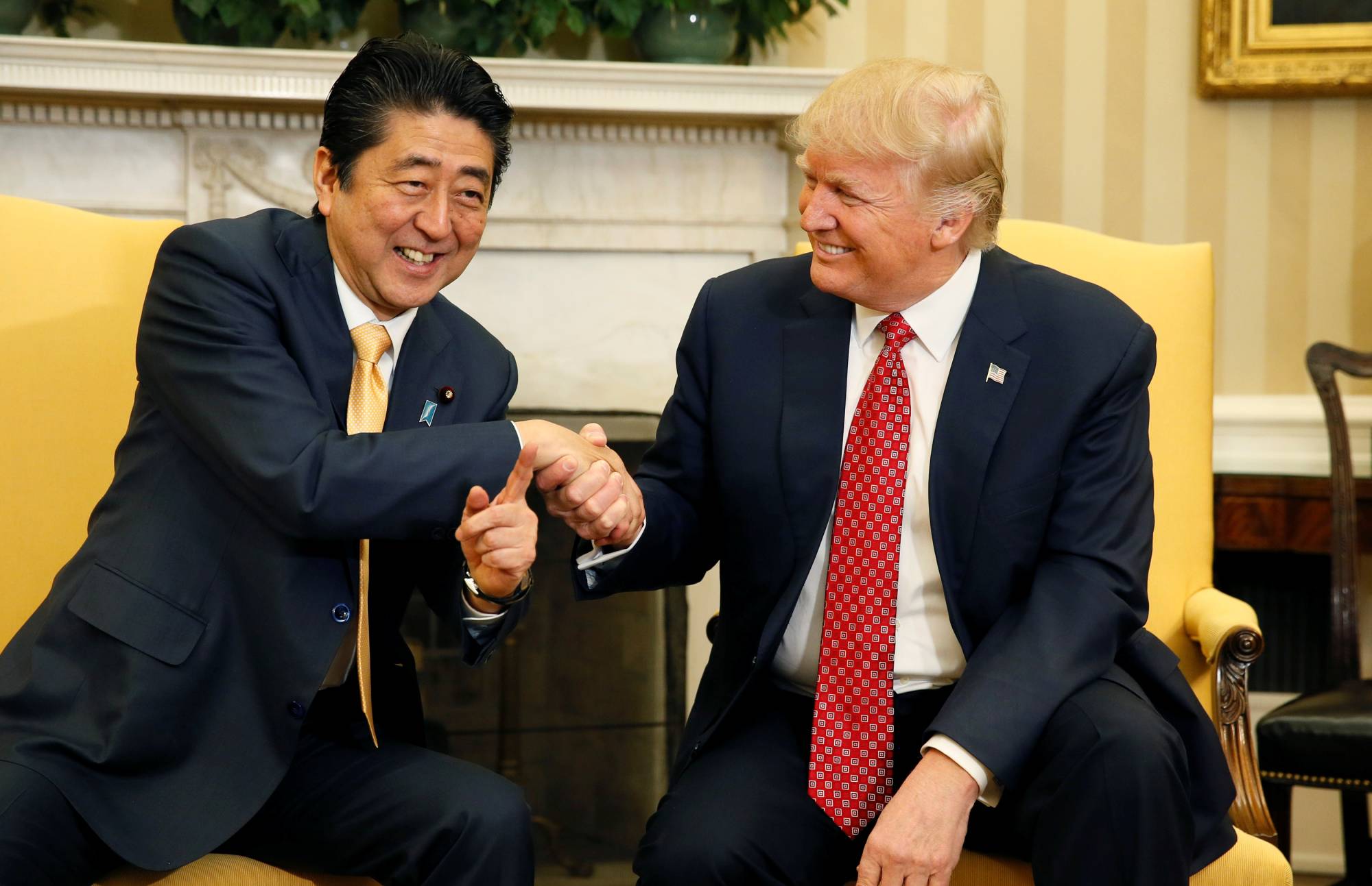 Prime Minister Shinzo Abe shakes hands with U.S. President Donald Trump during their meeting in the Oval Office at the White House in Washington in February 2017. | REUTERS
