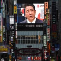 Prime Minister Shinzo Abe is seen on a large screen during a live news conference in Tokyo on Friday. | AFP-JIJI