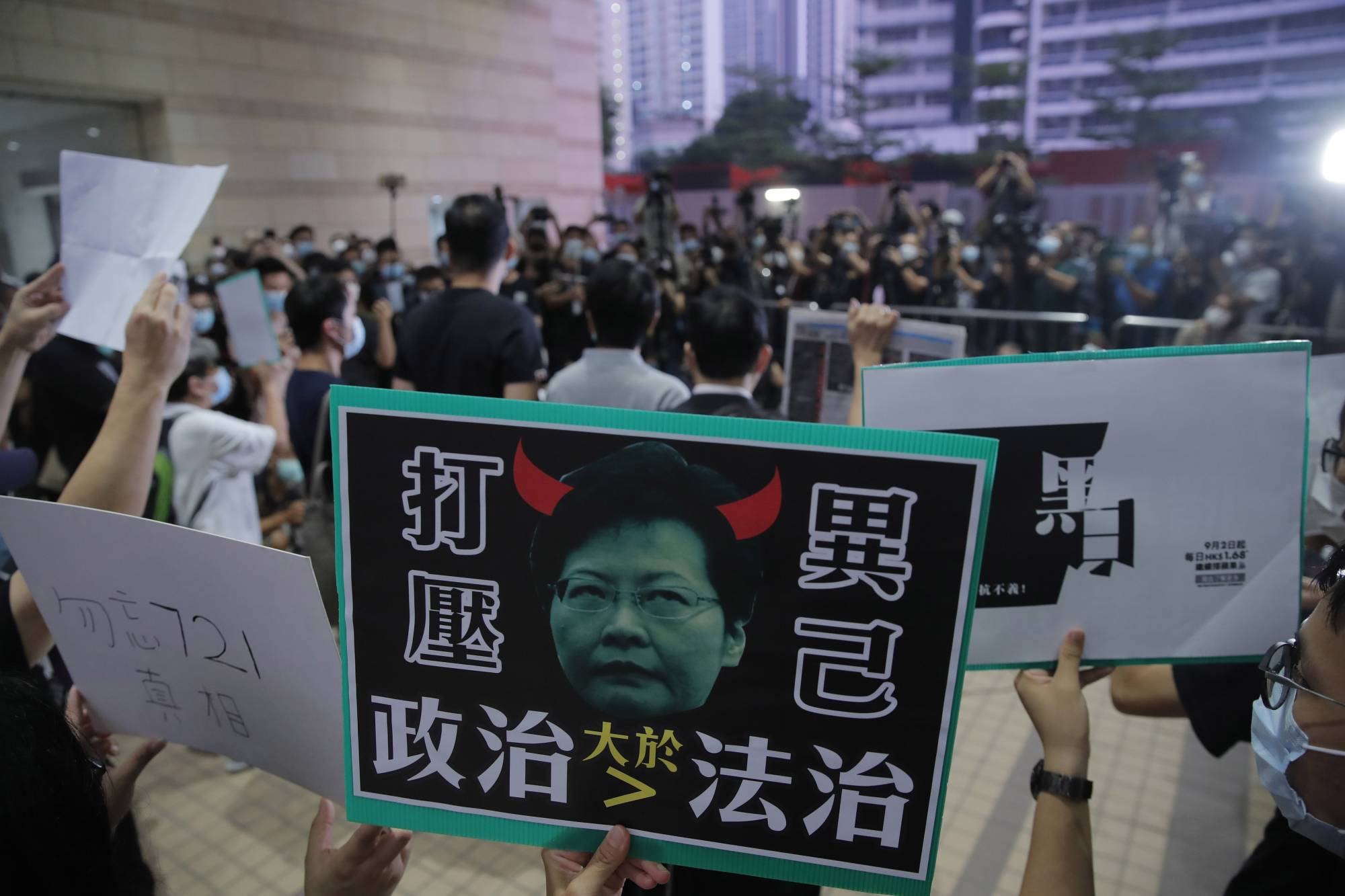 Pro-democracy protesters hold a placard featuring a picture of Hong Kong Chief Executive Carrie Lam as the pro-democracy legislators Ted Hui and Lam Cheuk-ting speak to media after being released on bail outside a court in Hong Kong on Thursday.  | AP
