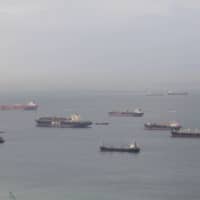 Ships sit offshore in the Singapore Strait in 2018. | BLOOMBERG