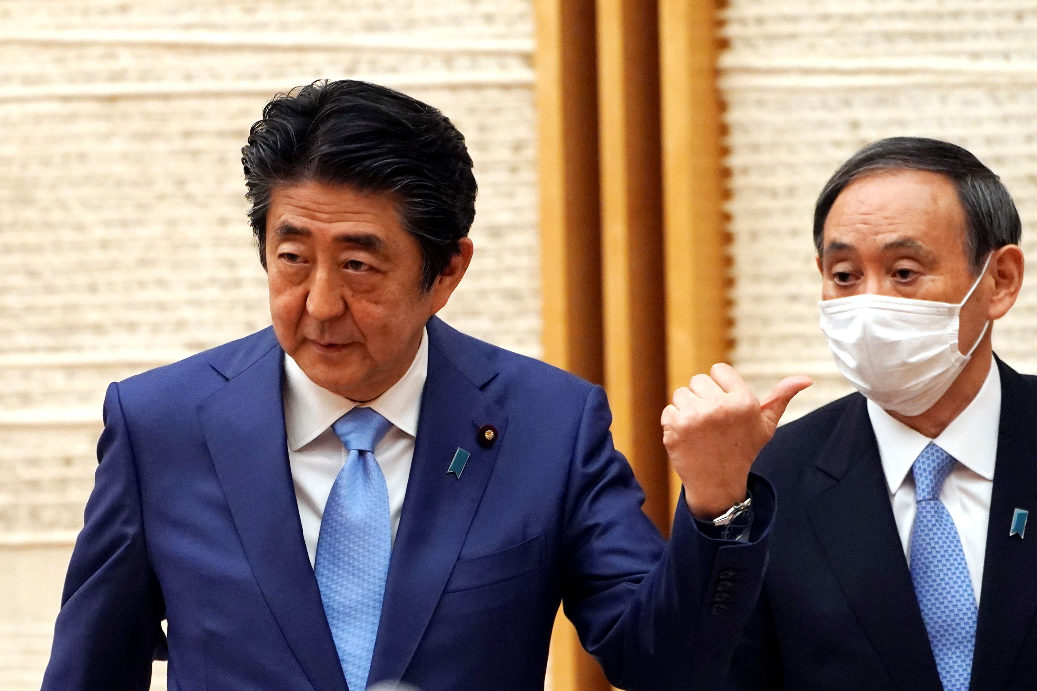 Prime Minister Shinzo Abe and Chief Cabinet Secretary Yoshihide Suga attend a May news conference in Tokyo. Suga, once thought of as a dark horse candidate to succeed Abe, has emerged as the front-runner in the race. | POOL / VIA REUTERS