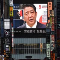 Prime Minister Shinzo Abe is seen on a large screen during a live press conference on Aug. 28. | AFP-JIJI