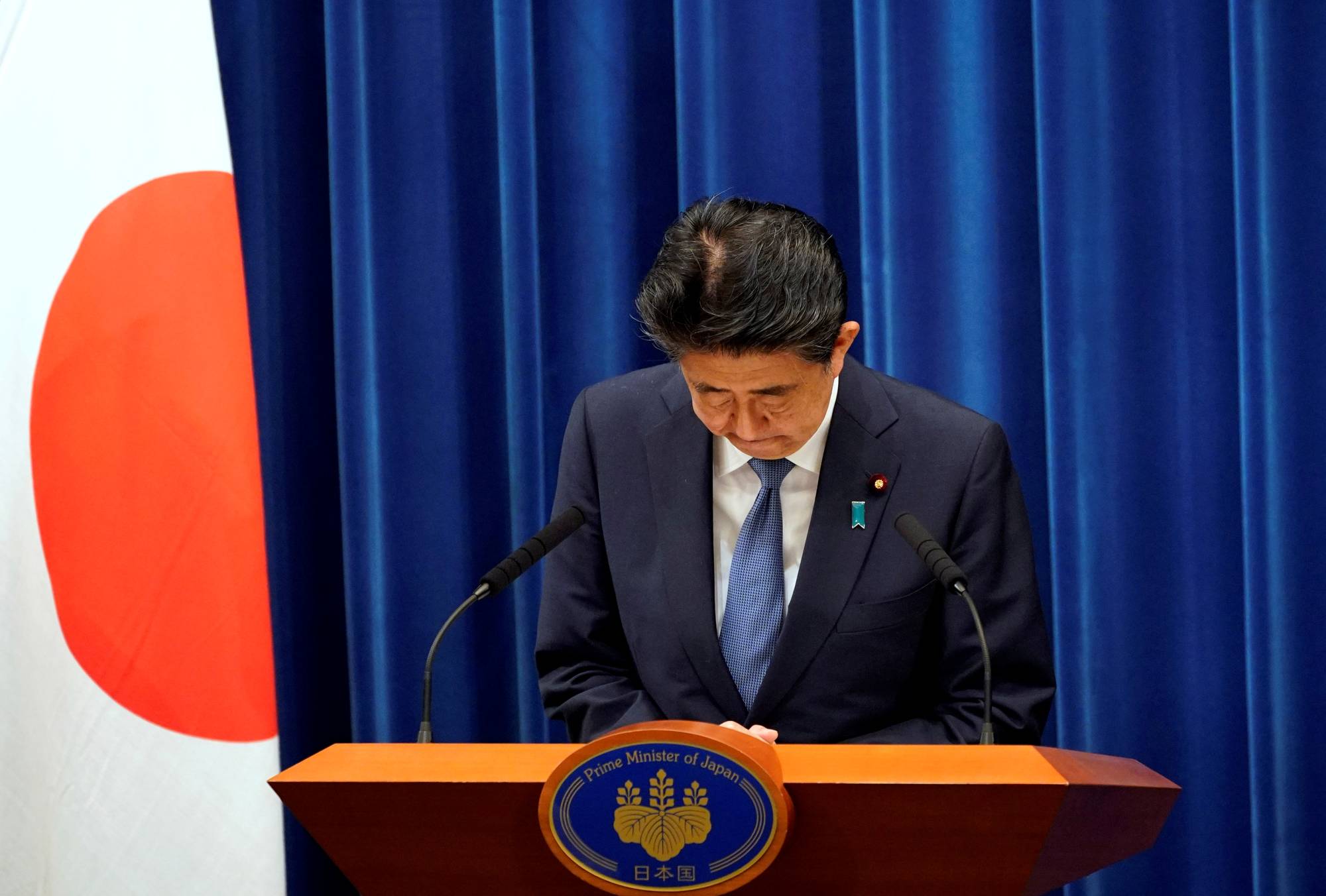 Prime Minister Shinzo Abe bows during a news conference at the Prime Minister's Office in Tokyo on Friday, during which he announced his intention to step down. | POOL / VIA REUTERS