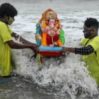 People wearing protective masks due to the COVID-19 pandemic carry an idol of the Hindu god Ganesh, the deity of prosperity, for immersion off the coast of the Arabian sea during the Ganesh Chaturthi festival in Mumbai on Aug. 23. | REUTERS