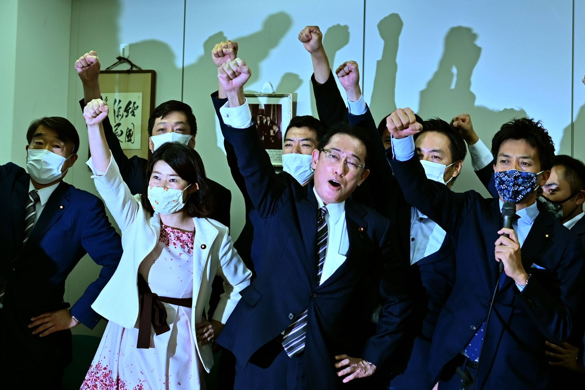 LDP Policy Research Council Chairman Fumio Kishida (center) raises his fist in the air with his faction members after announcing his candidacy for the LDP leadership during a meeting in Tokyo on Tuesday. | AFP