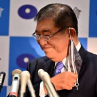 Former Defense Minister Shigeru Ishiba takes off his face mask as he attends a news conference to announce his candidacy for the LDP leadership in Tokyo on Tuesday. |  AFP