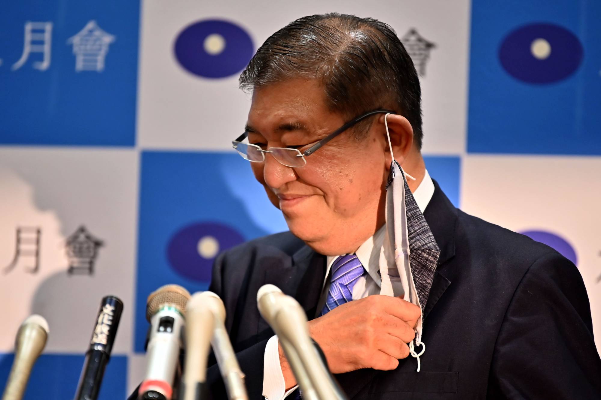 Former Defense Minister Shigeru Ishiba takes off his face mask as he attends a news conference to announce his candidacy for the LDP leadership in Tokyo on Tuesday. |  AFP