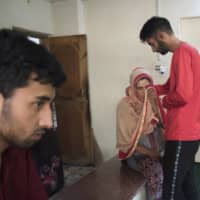 Shaheen Sajad is comforted by her eldest son, Sameer Ahmad, while her youngest son Salman Sajad looks on at their house in Vessu, India.  | SHOWKAT NANDA/THE NEW YORK TIMES
