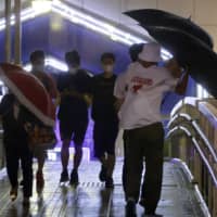 People walk in strong winds in Nagasaki Prefecture on Wednesday as Typhoon Maysak passed near the Kyushu region. | KYODO