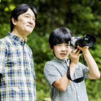 Prince Hisahito takes pictures as Crown Prince Akishino looks on at their residence in Tokyo\'s Akasaka district in August. | IMPERIAL HOUSEHOLD AGENCY / VIA KYODO