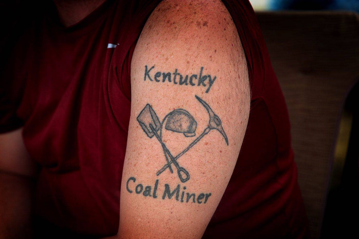 Unemployed Blackjewel coal miner Chris Lewis shows his tattoo as he participates in a blockade along the railroad tracks that lead to one of Blackjewel's mines on Aug. 8, 2019, near Cumberland, Kentucky. | GETTY IMAGES / VIA BLOOMBERG