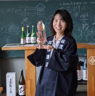 Rumiko Obata, executive vice president of Obata Sake Brewery, holds the Grand Prize trophy in the Satoyama category at Gakkogura brewery, which used to be an elementary school, on Sado Island, Niigata Prefecture. | OBATA SAKE BREWERY