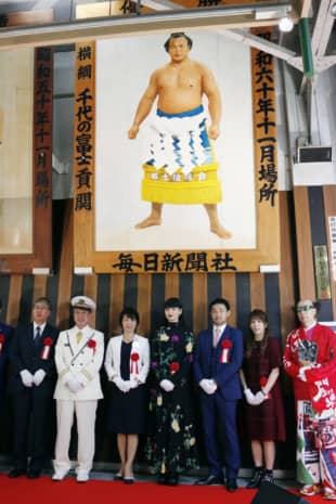 Three-time Olympic women's wrestling gold medalist Saori Yoshida (second from right) and others pose under a portrait of former yokozuna Chiyonofuji at JR Ryogoku station in Sumida Ward. | POOL / VIA KYODO