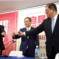 Liberal Democratic Party leadership candidates Chief Cabinet Secretary Yoshihide Suga (center), former Foreign Minister Fumio Kishida (left) and former Defense Minister Shigeru Ishiba pose during a news conference at the party headquarters in Tokyo on Tuesday. | POOL VIA REUTERS