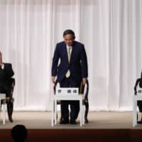 Chief Cabinet Secretary Yoshihide Suga (center), former Foreign Minister Fumio Kishida (right) and former Defense Minister Shigeru Ishiba (left) attend a speech session in Tokyo on Tuesday as part of their campaigns in the Liberal Democratic Party\'s (LDP) leadership election. | POOL / VIA AP