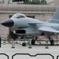 A soldier stands next to a J-10 fighter jet during an exhibition outside the Military Museum of the Chinese People\'s Revolution in Beijing. | REUTERS