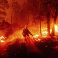 A firefighter battles the Creek Fire as it threatens homes in the Cascadel Woods neighborhood of Madera County, California, on Monday. | AP