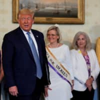 Cleta Mitchell (second from right), a prominent Republican lawyer who chairs an Indiana-based group dedicated to election integrity, watches as U.S. President Donald Trump arrives for a signing ceremony in August.  | REUTERS