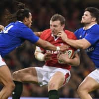 Wales center Hadleigh Parkes (center) is tackled during a Six Nations match between Wales and France on Feb. 22 in Cardiff. | AFP-JIJI