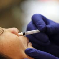 A woman receives an H1N1 flu nasal spray vaccination in San Francisco in 2009. | GETTY IMAGES / VIA BLOOMBERG