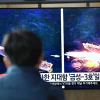 A man watches a television news broadcast showing file footage of a North Korean missile test at a railway station in Seoul on April 14. | AFP-JIJI