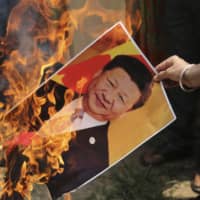 A Bharatiya Janata Party activist burns a photograph of Chinese President Xi Jinping during a protest in Jammu, India, in July. A bitter military standoff between India and China has pushed New Delhi closer to the U.S., Australia and Japan. | AP