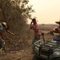 Workers rest after trying to put out a fire on a ranch in the Pantanal. | REUTERS 