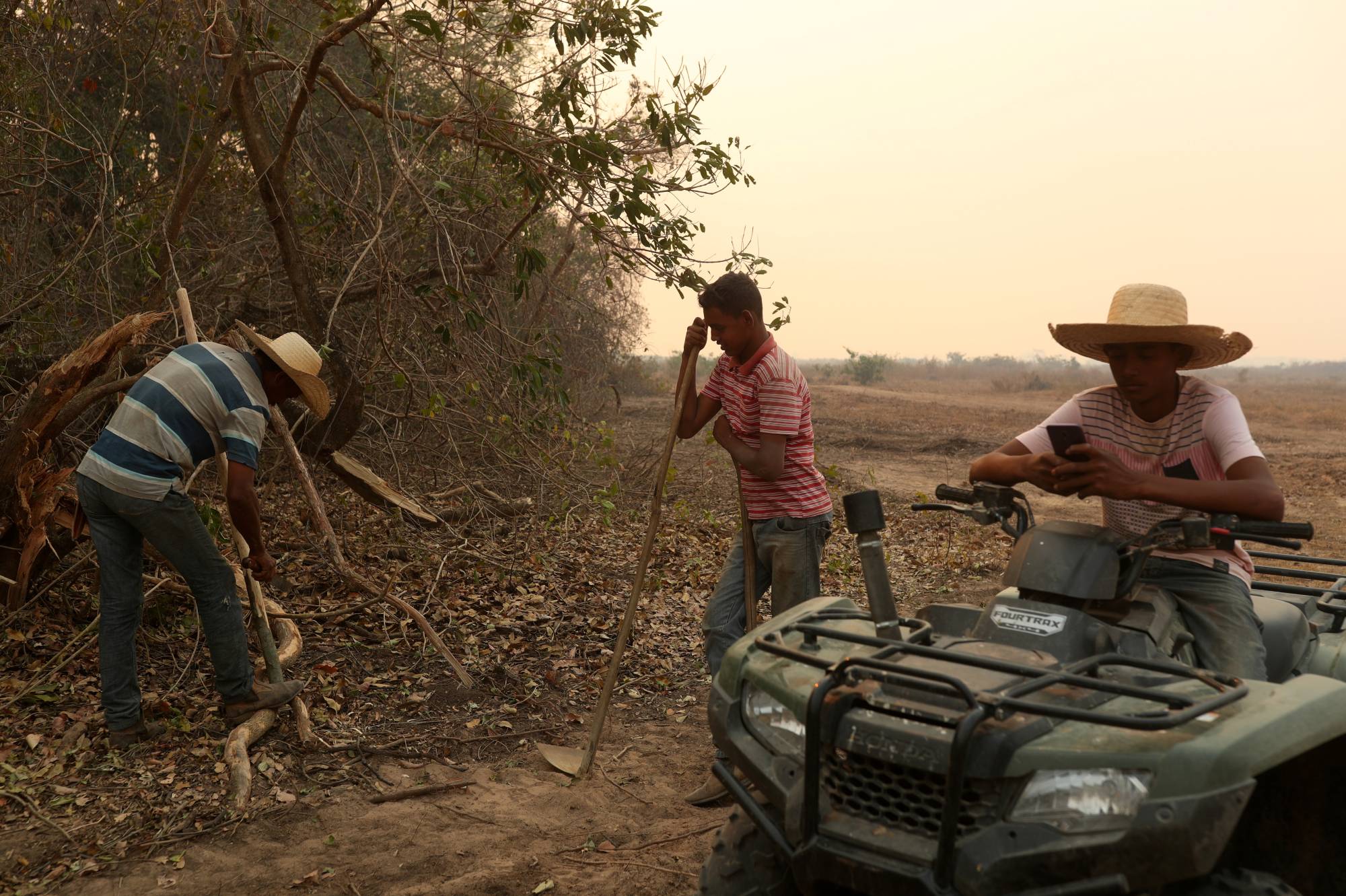Workers rest after trying to put out a fire on a ranch in the Pantanal. | REUTERS 