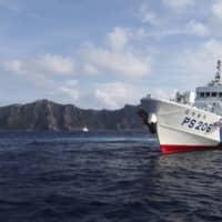 A Japan Coast Guard vessel sails in front of Uotsuri Island, one of the disputed Senkaku islets, in August 2013.  | REUTERS