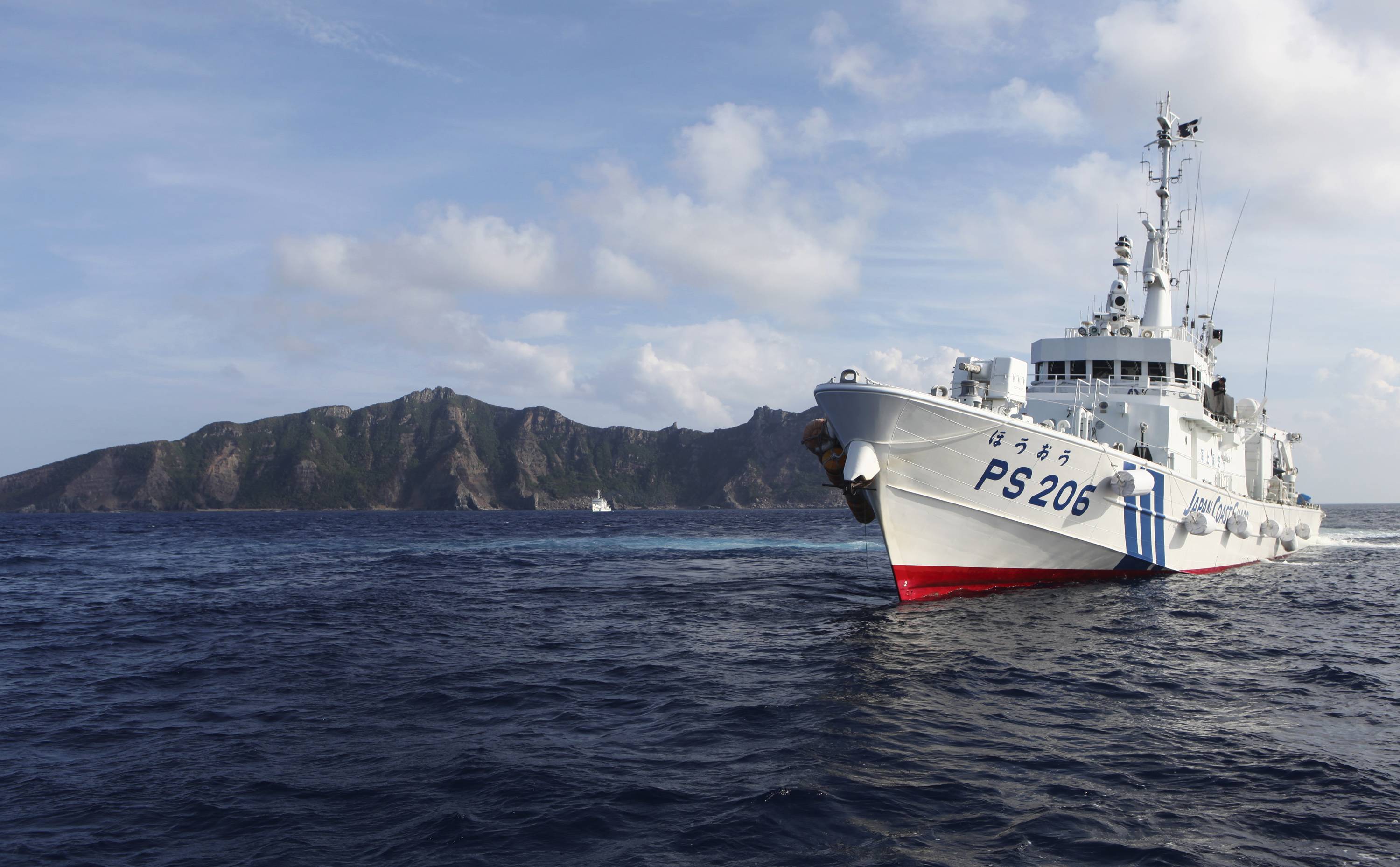 A Japan Coast Guard vessel sails in front of Uotsuri Island, one of the disputed Senkaku islets, in August 2013.  | REUTERS