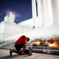 A man kneels at a vigil on the steps of the U.S. Supreme Court following the death of Justice Ruth Bader Ginsburg, in Washington on Friday.  | REUTERS
