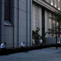Workers take a lunch break in Tokyo\'s Marunouchi district earlier this month amid the coronavirus pandemic. | BLOOMBERG