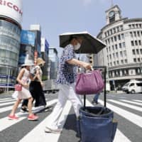 People walk in Tokyo\'s Ginza shopping district amid the scorching summer heat in August. | KYODO
