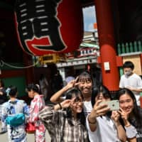 People pose at the entrance to Sensoji temple in Tokyo\'s Asakusa district on Tuesday. | AFP-JIJI